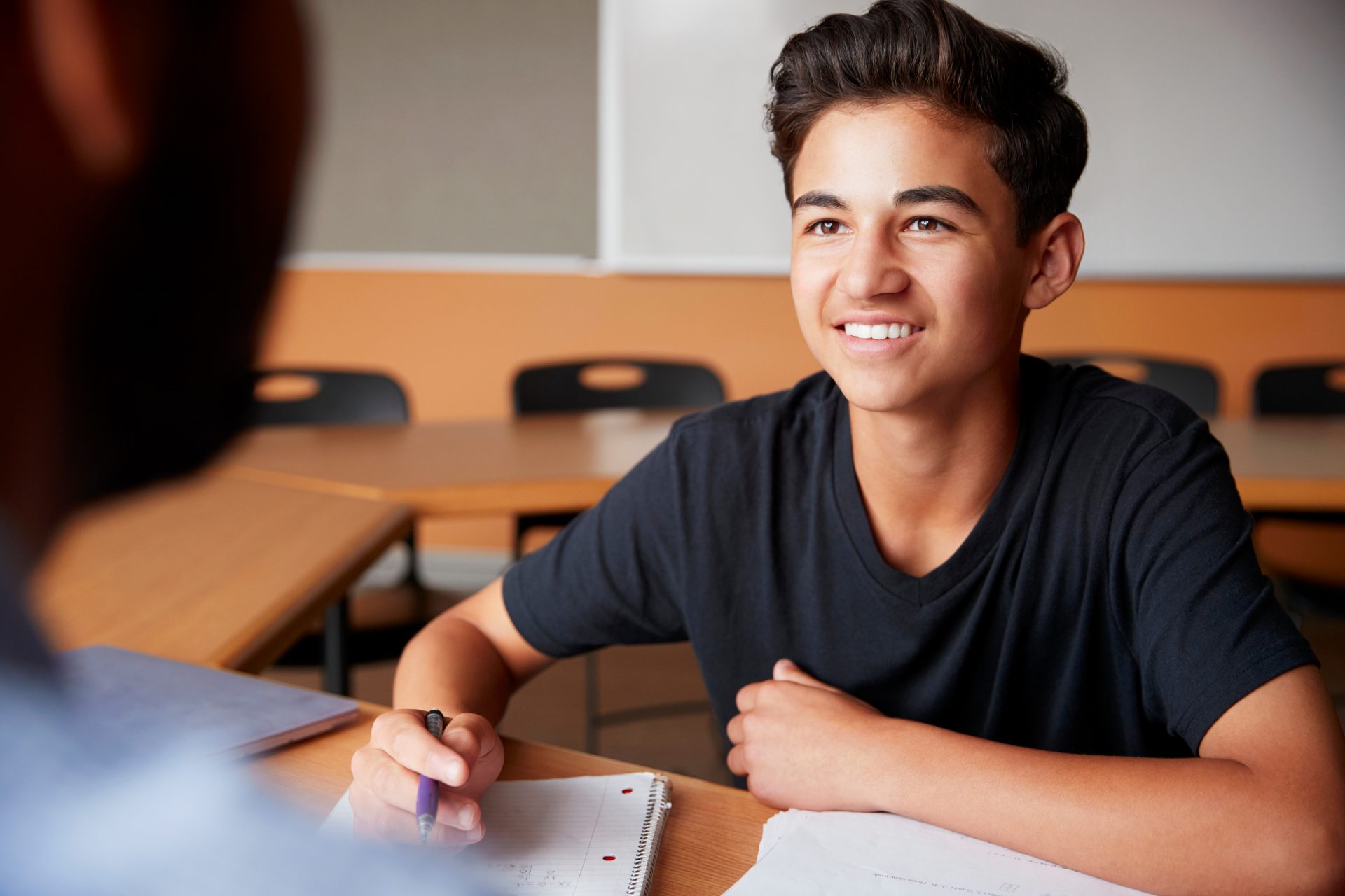 Hispanic student taking notes in class