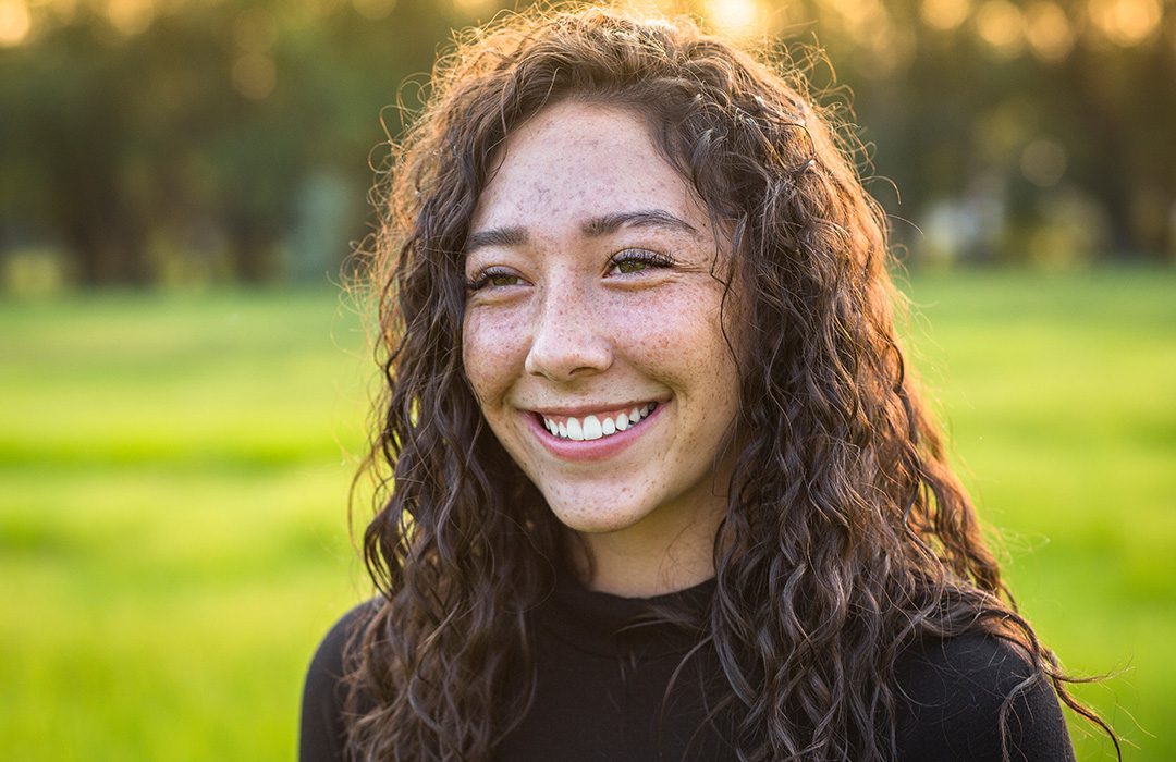 young person smiling while outside