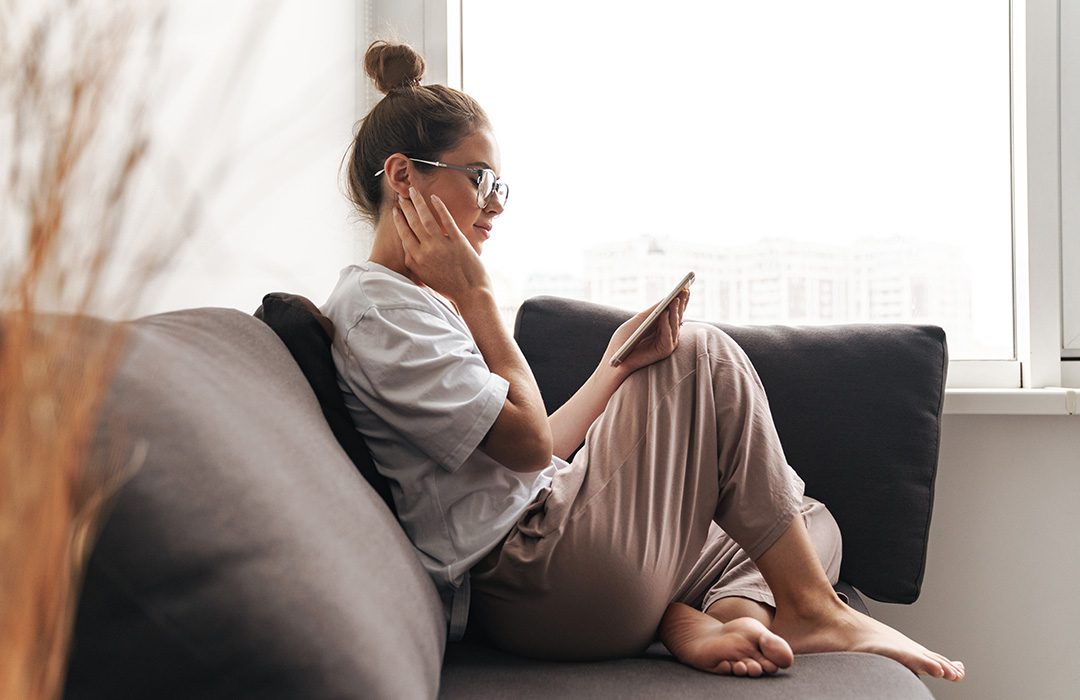 young person sitting on a couch looking at their cell phone