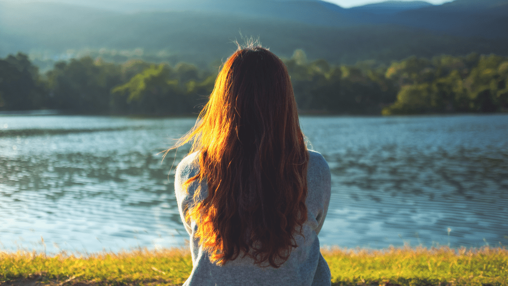 woman meditating through a depressive episode by a lake