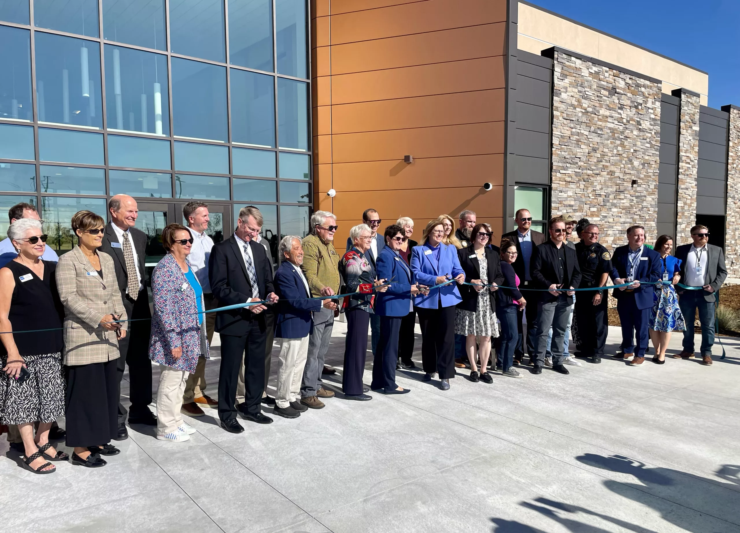 group of people outside a building doing a ribbon cutting