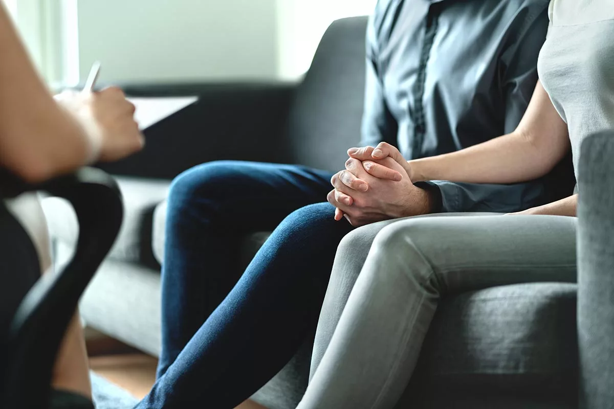 close up of people holding hands and talking to a therapist