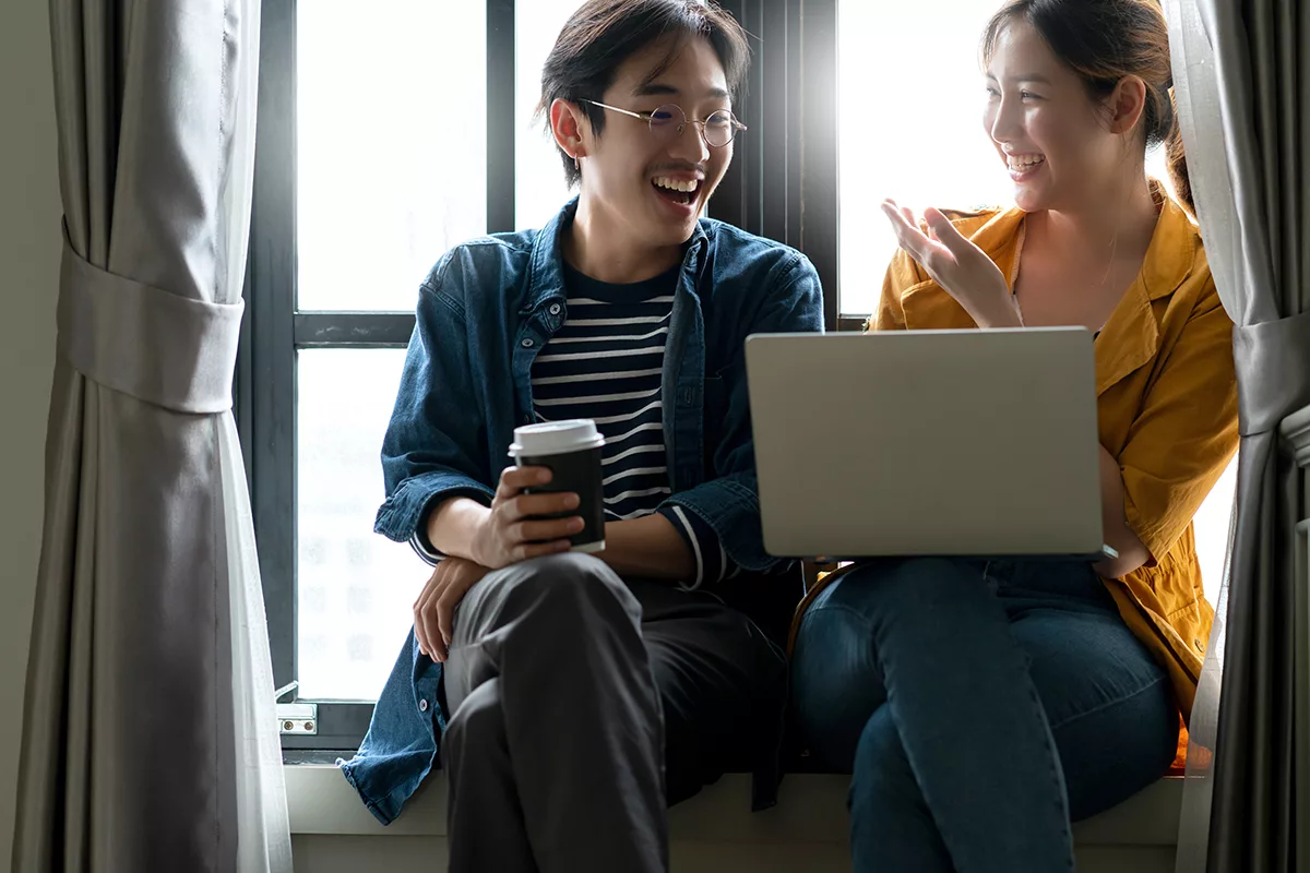 couple sitting together near each other looking at computer