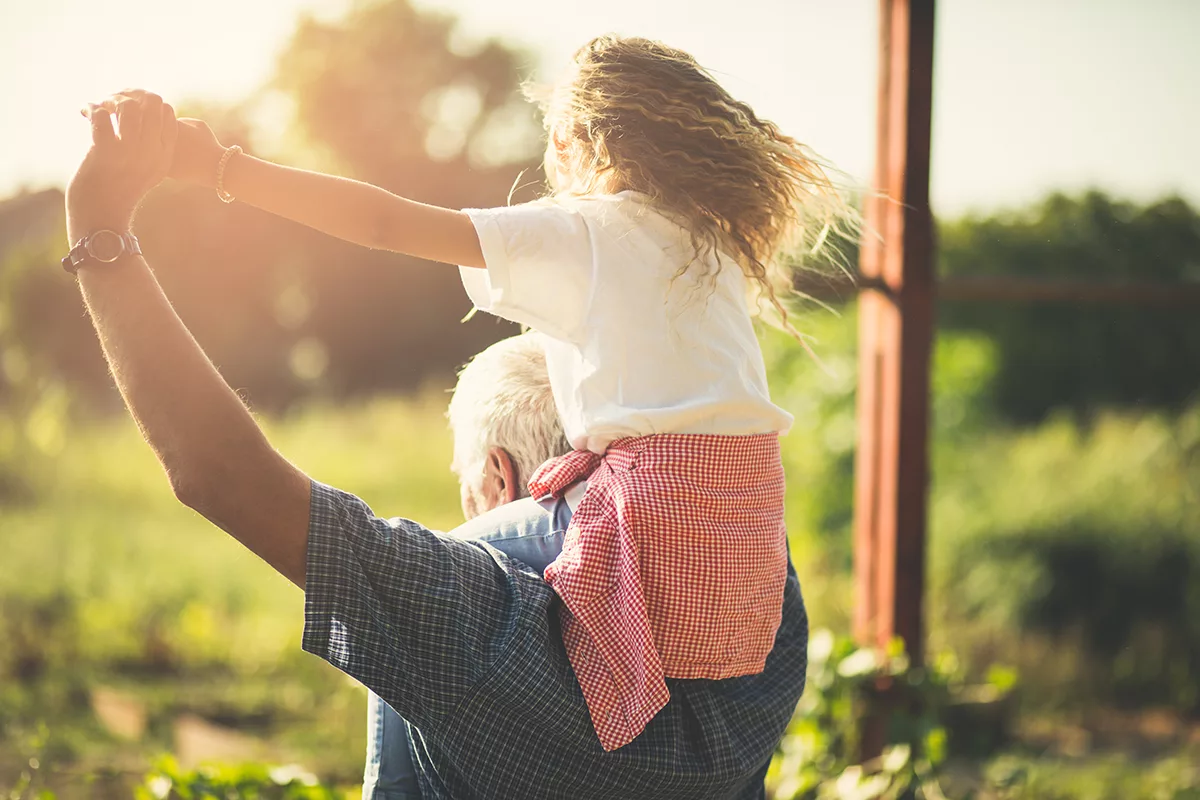 grandfather with granddaughter on his shoulders