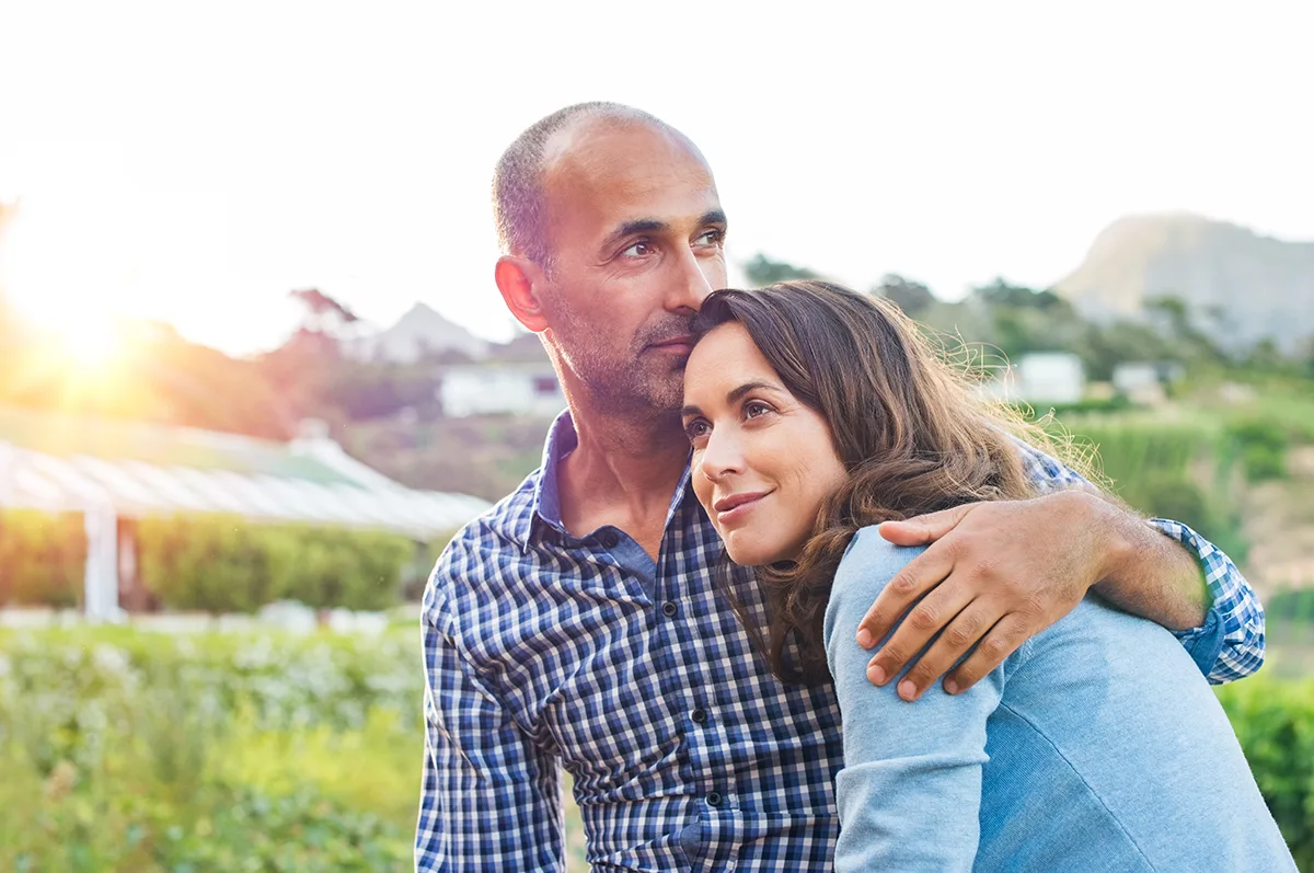 man with arm around woman walking in a field