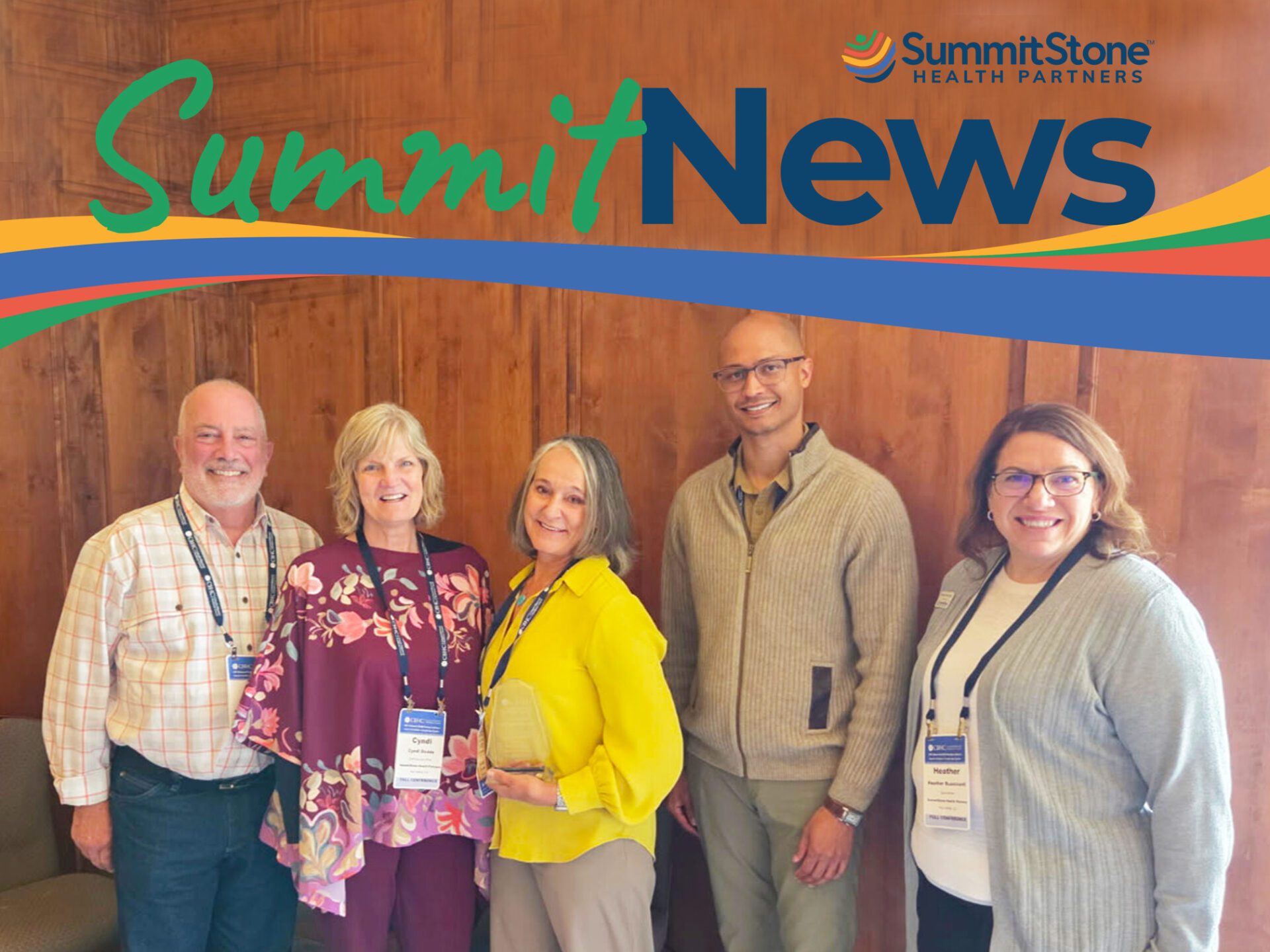 Five smiling adults stand together indoors, wearing conference badges. Behind them is a wood-paneled wall. "SummitNews" and the SummitStone Health Partners logo appear at the top of the image.